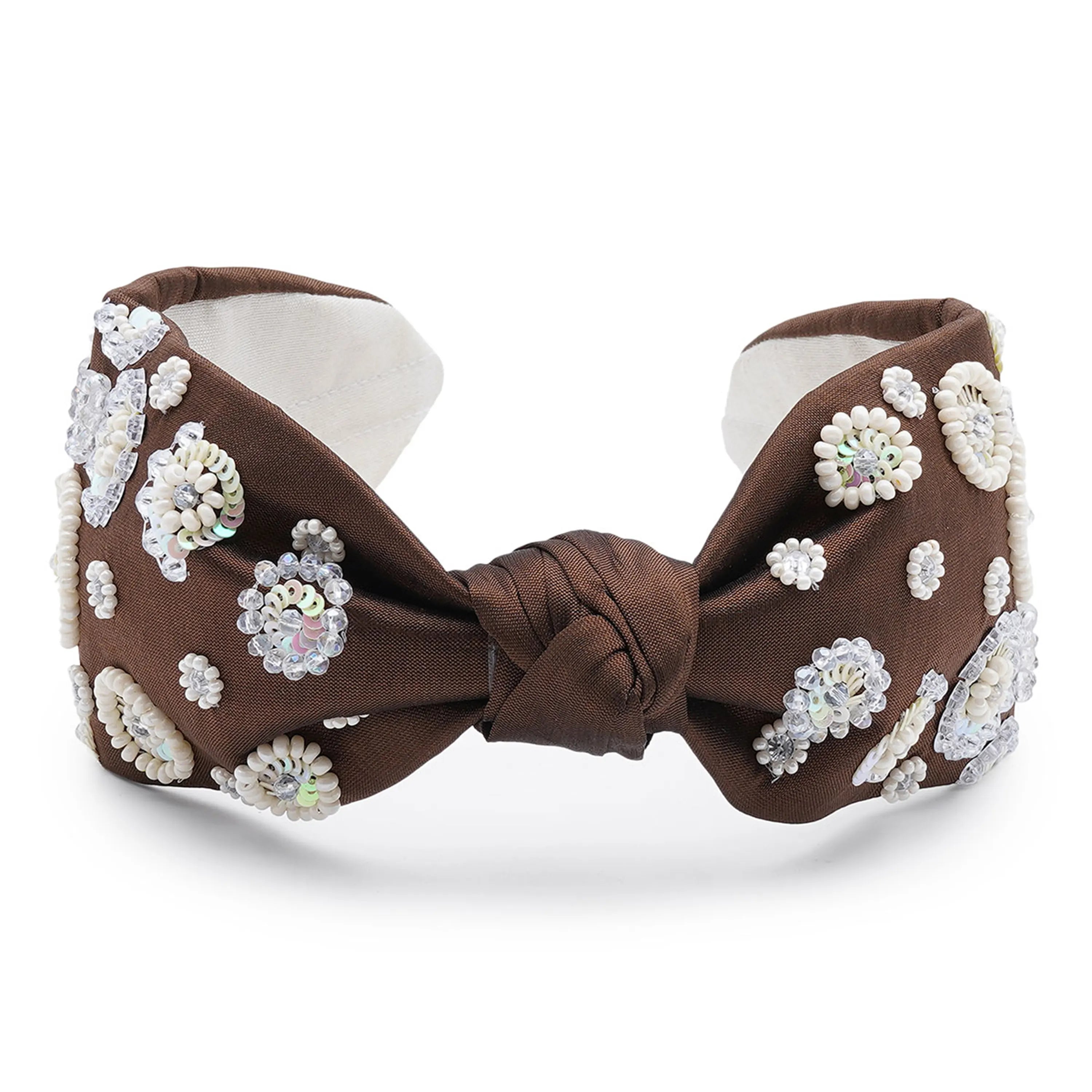 A brown satin headband with a white fabric top decorated with a vintage floral circle pattern embellished with rhinestones.